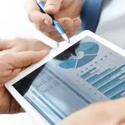 A businessperson checking graphs and charts on a tablet. An example of how semiconductors made from silicon wafers are used in electronic devices.