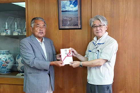 Two men presenting a monetary gift at a donation ceremony for a horseshoe crab conservation group (2022).