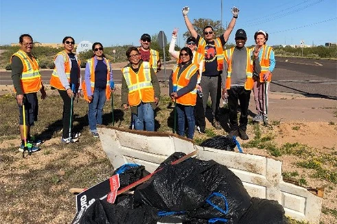 Participants of a cleaning activity in the U.S. posing in front of the bags of trash they collected.