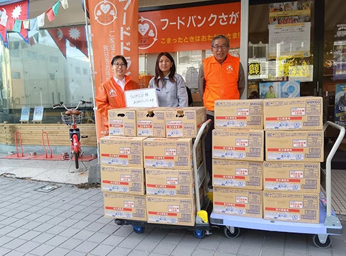 A commemorative photo of three officials posing in front of cardboard boxes of stockpiled water.