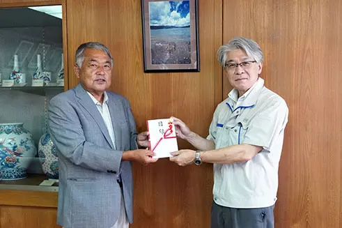カブトガニ保護活動団体への寄付金贈呈式で祝儀袋を手渡す2名の男性（2022年）