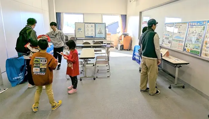 半導体セミナーの会場で、子どもたちと大人が展示パネルを見学している様子